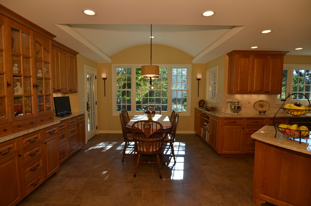 Example of a classic u-shaped eat-in kitchen design in Portland with an undermount sink, raised-panel cabinets, light wood cabinets, granite countertops, beige backsplash, terra-cotta backsplash and stainless steel appliances