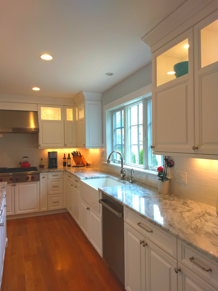 Inredning av ett eklektiskt stort flerfärgad flerfärgat kök, med en rustik diskho, luckor med infälld panel, vita skåp, bänkskiva i kvartsit, vitt stänkskydd, stänkskydd i tunnelbanekakel, rostfria vitvaror, ljust trägolv, en köksö och brunt golv