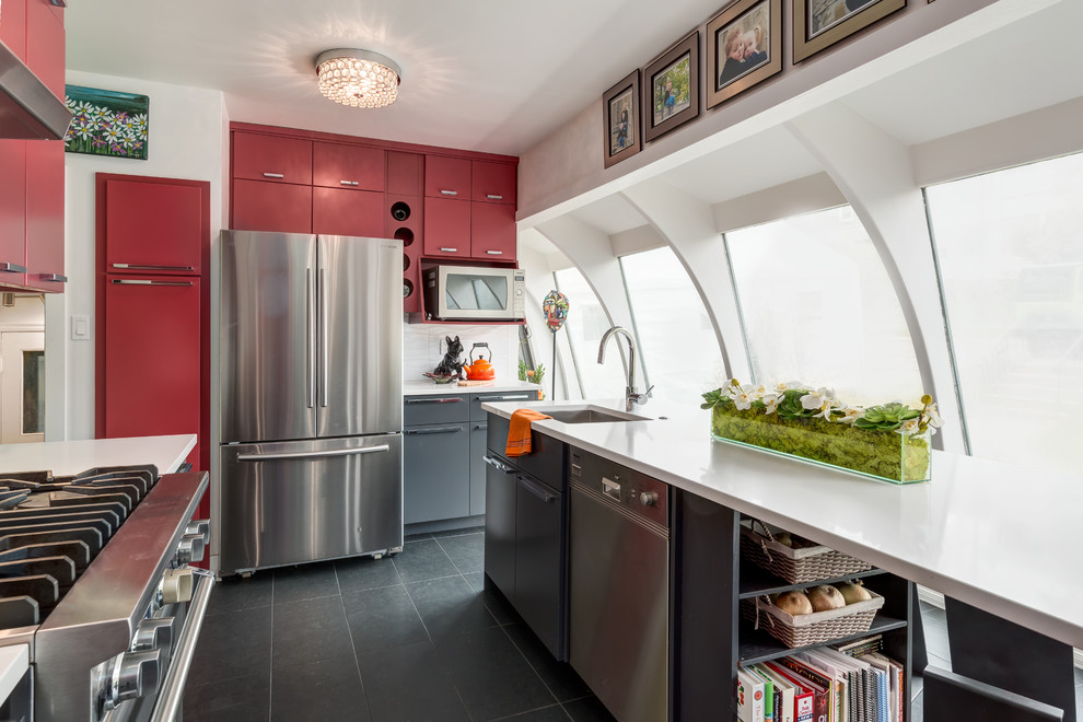 Photo of a medium sized modern galley enclosed kitchen in Calgary with a submerged sink, flat-panel cabinets, red cabinets, white splashback, porcelain flooring, an island, engineered stone countertops, ceramic splashback and stainless steel appliances.