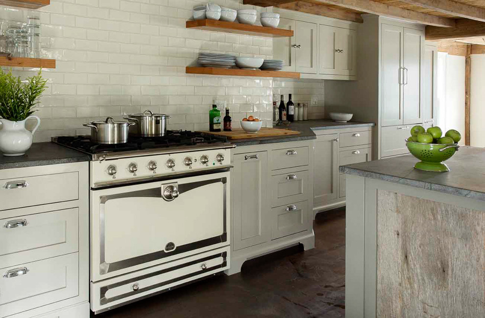 Small farmhouse galley dark wood floor eat-in kitchen photo in Boston with a farmhouse sink, recessed-panel cabinets, gray cabinets, soapstone countertops, white backsplash, ceramic backsplash, white appliances and an island