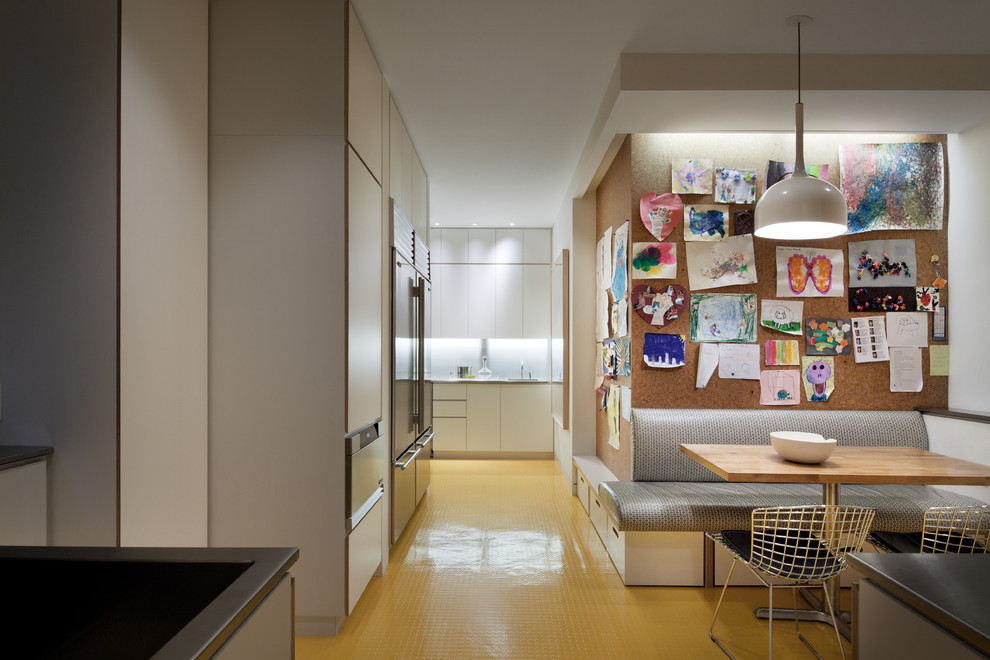 Große Moderne Wohnküche mit flächenbündigen Schrankfronten, weißen Schränken, Küchenrückwand in Weiß, Küchengeräten aus Edelstahl und gelbem Boden in Auckland
