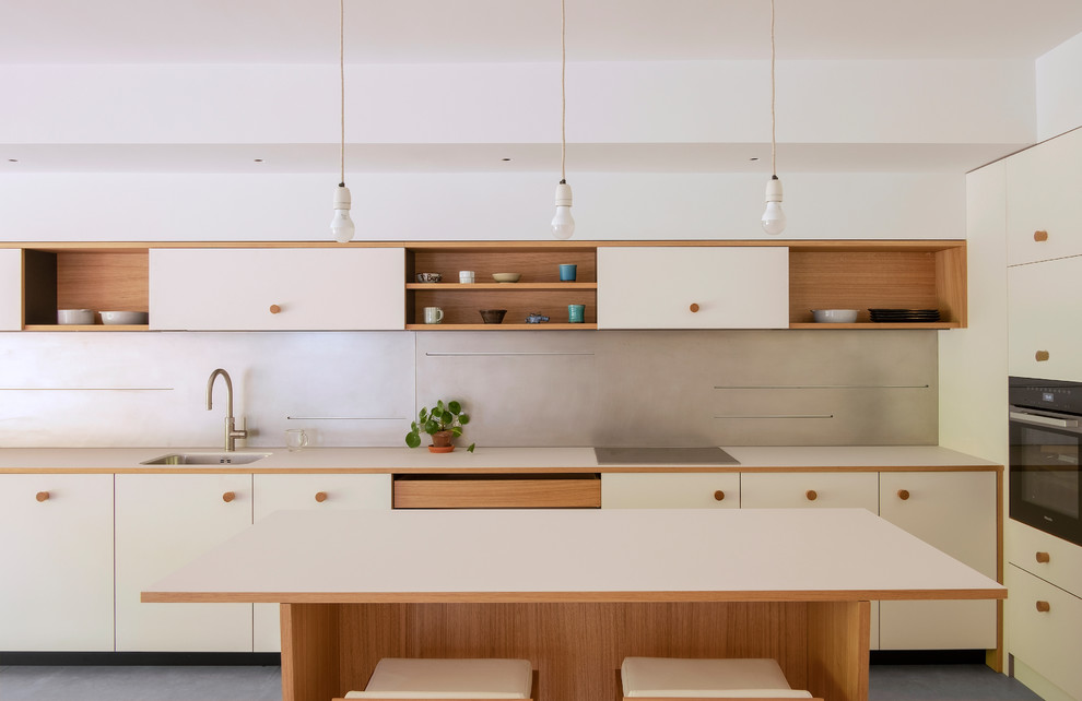 Contemporary l-shaped kitchen in London with a submerged sink, flat-panel cabinets, white cabinets, an island, grey floors and white worktops.