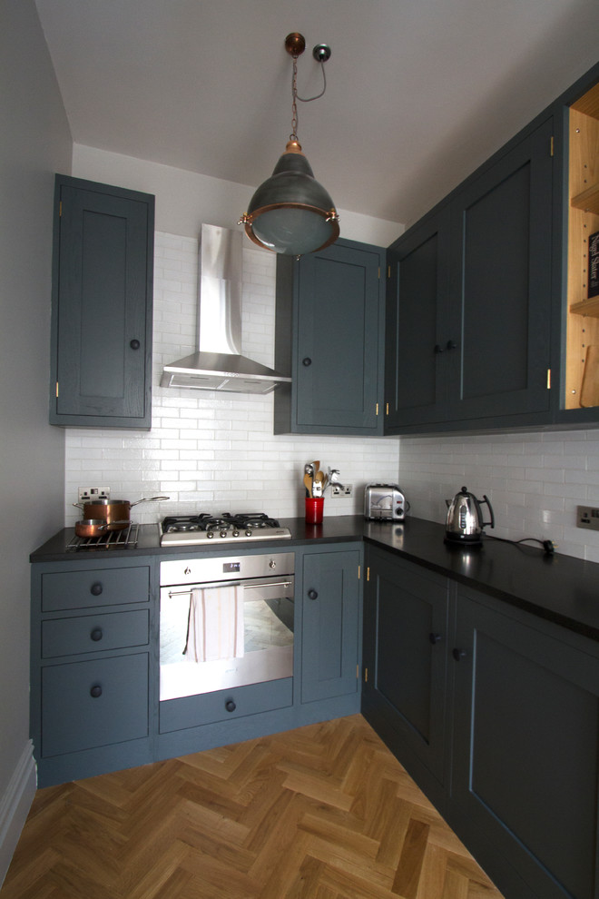 Small contemporary l-shaped enclosed kitchen in Other with a submerged sink, shaker cabinets, granite worktops, white splashback, stainless steel appliances, medium hardwood flooring, no island, grey cabinets and metro tiled splashback.