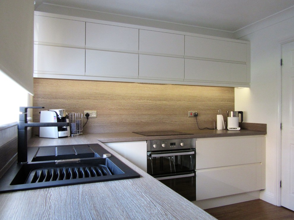 Imagen de cocinas en L contemporánea de tamaño medio abierta sin isla con armarios con paneles lisos, puertas de armario blancas y encimera de laminado