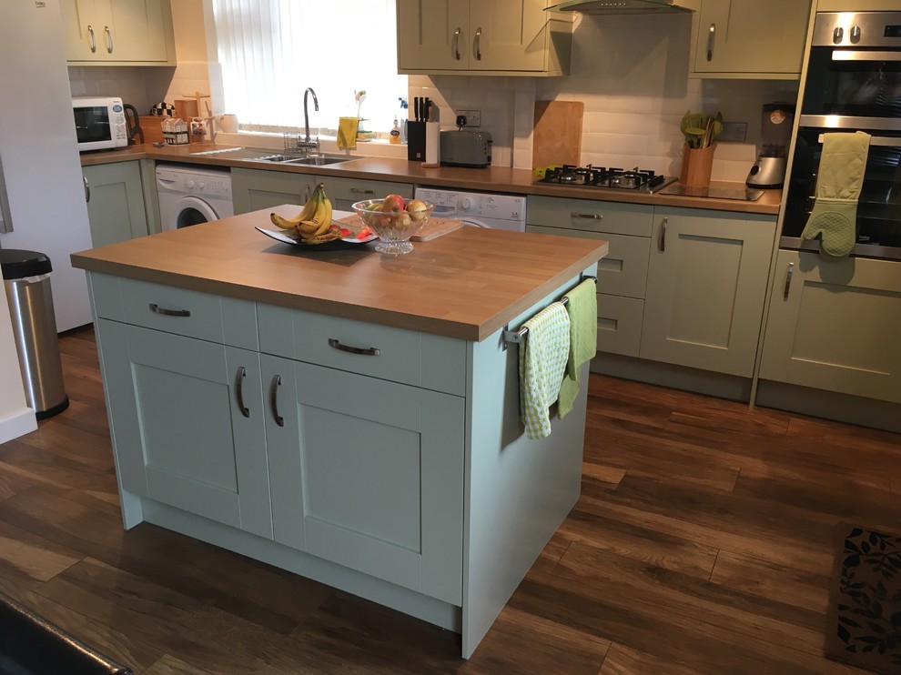 This is an example of a medium sized farmhouse l-shaped kitchen/diner in Other with shaker cabinets, green cabinets, wood worktops and an island.