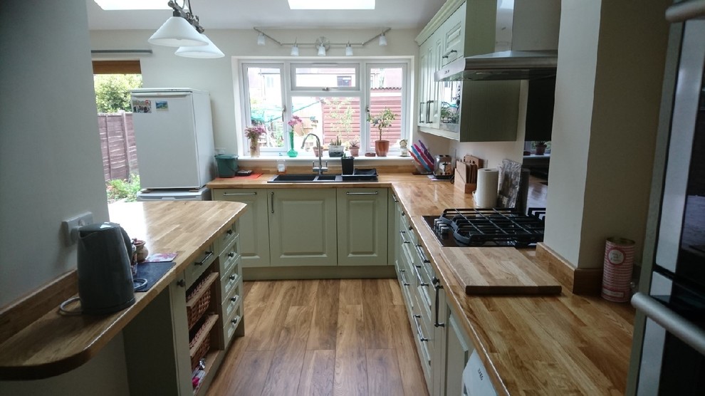 This is an example of a medium sized classic l-shaped kitchen/diner in Cheshire with shaker cabinets, green cabinets, wood worktops and a breakfast bar.
