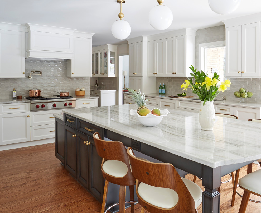 Inspiration for a traditional kitchen in Chicago with a submerged sink, recessed-panel cabinets, white cabinets, grey splashback, stainless steel appliances, medium hardwood flooring, an island, brown floors and grey worktops.