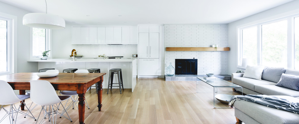 Example of a mid-sized minimalist single-wall light wood floor and beige floor open concept kitchen design in Ottawa with an undermount sink, flat-panel cabinets, white cabinets, white backsplash, paneled appliances, a peninsula and white countertops