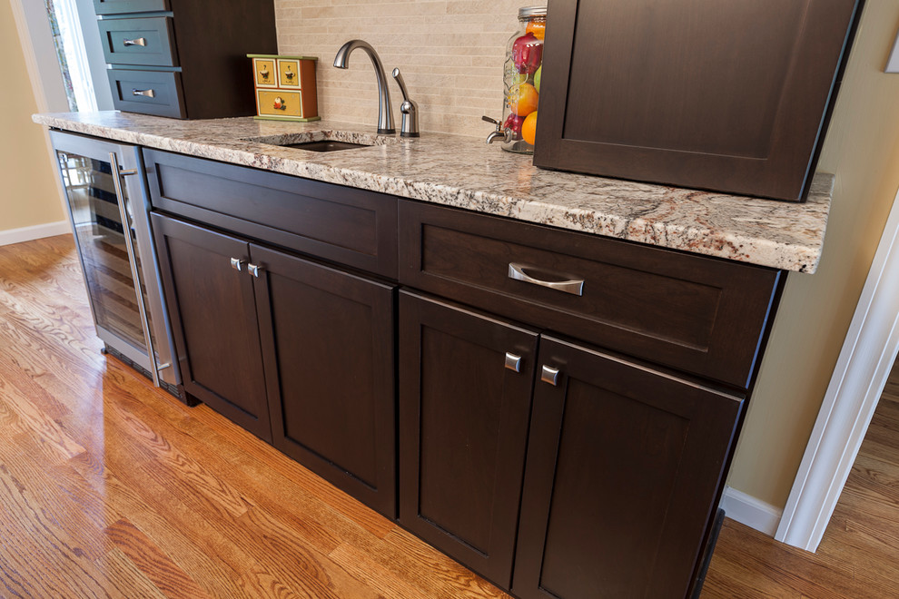 Inspiration for a large transitional l-shaped medium tone wood floor eat-in kitchen remodel in Bridgeport with an undermount sink, shaker cabinets, dark wood cabinets, granite countertops, beige backsplash, porcelain backsplash, stainless steel appliances and an island