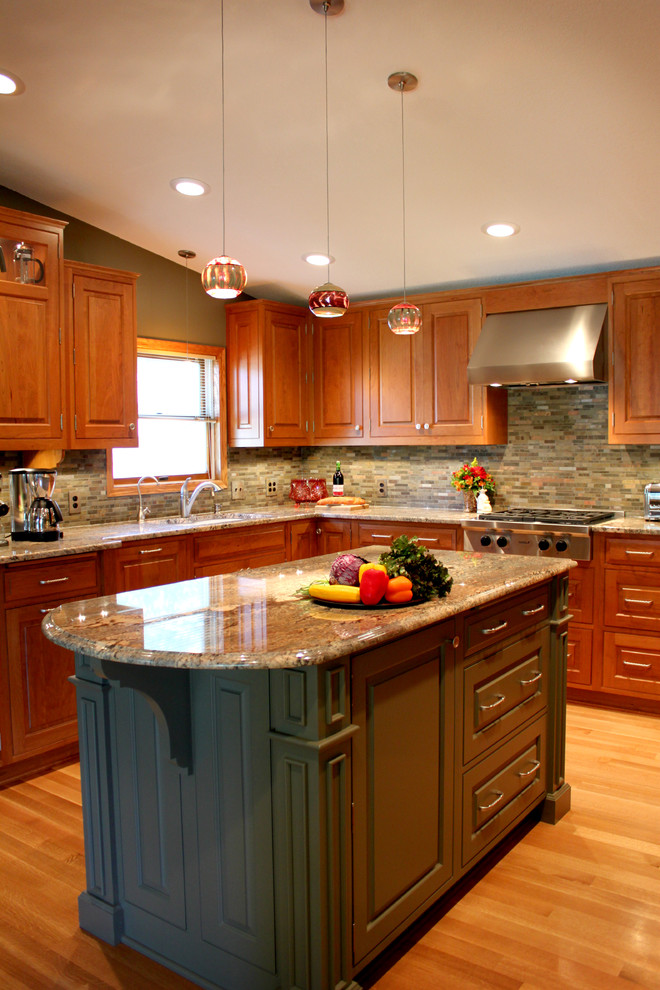Bild på ett mellanstort vintage kök, med en dubbel diskho, luckor med upphöjd panel, skåp i mellenmörkt trä, granitbänkskiva, grönt stänkskydd, stänkskydd i stenkakel, rostfria vitvaror, ljust trägolv och en köksö