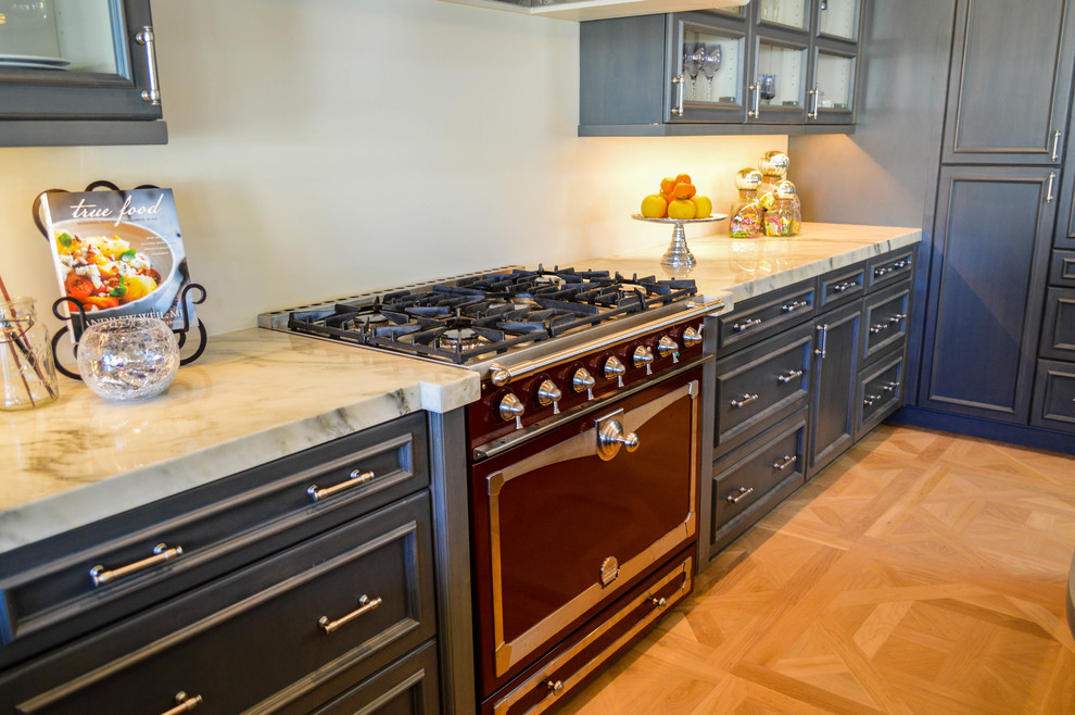 Elegant u-shaped medium tone wood floor kitchen photo in Seattle with a farmhouse sink, recessed-panel cabinets, blue cabinets, stainless steel appliances and an island