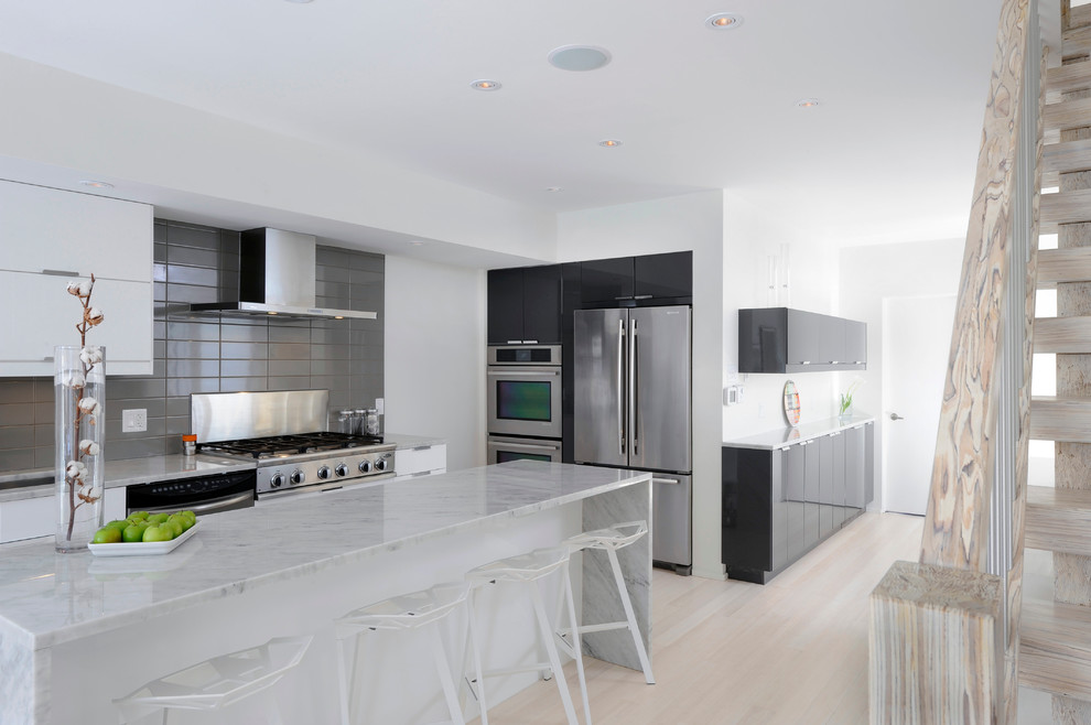 Exempel på ett mellanstort nordiskt linjärt kök och matrum, med en undermonterad diskho, släta luckor, vita skåp, marmorbänkskiva, grått stänkskydd, stänkskydd i porslinskakel, rostfria vitvaror, ljust trägolv och en köksö