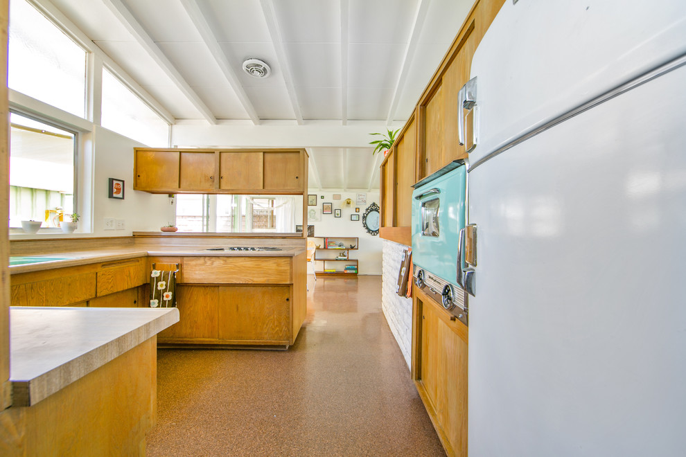 На фото: п-образная кухня среднего размера в стиле ретро с накладной мойкой, светлыми деревянными фасадами, столешницей из ламината и цветной техникой с