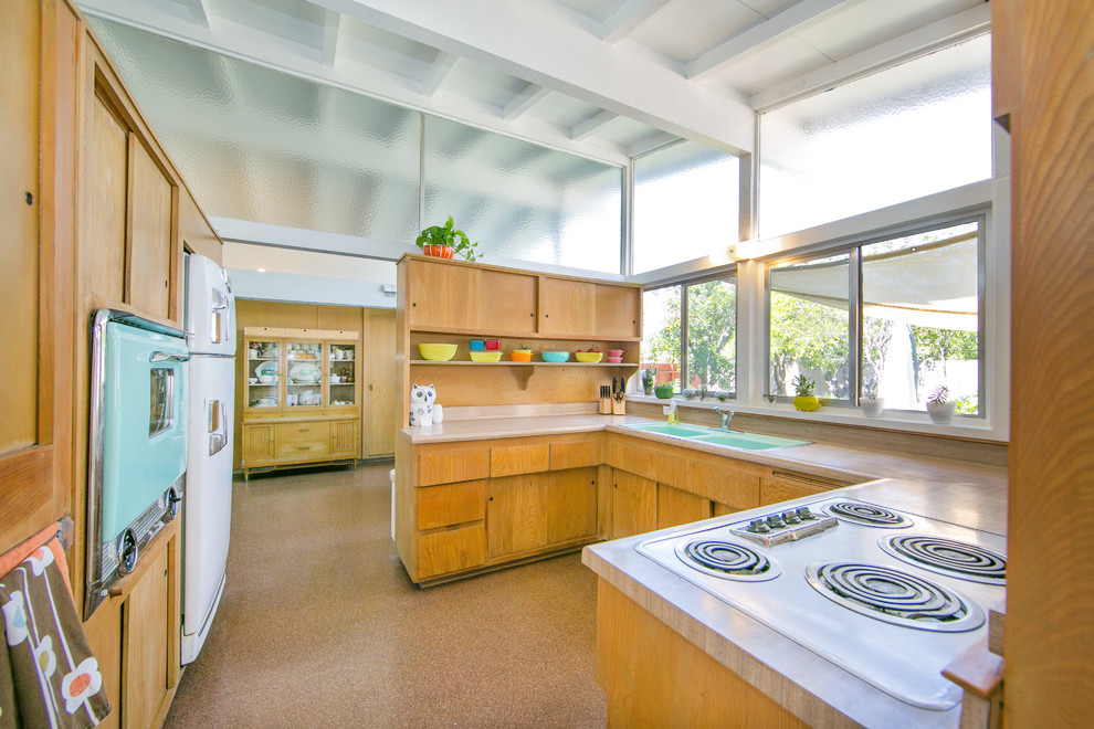 На фото: п-образная кухня среднего размера в стиле ретро с накладной мойкой, светлыми деревянными фасадами, столешницей из ламината и цветной техникой