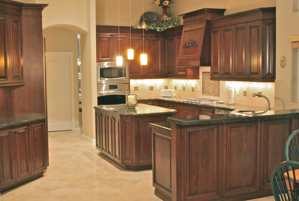 Medium sized traditional u-shaped kitchen/diner in Phoenix with a submerged sink, raised-panel cabinets, dark wood cabinets, granite worktops, stainless steel appliances, an island and beige floors.