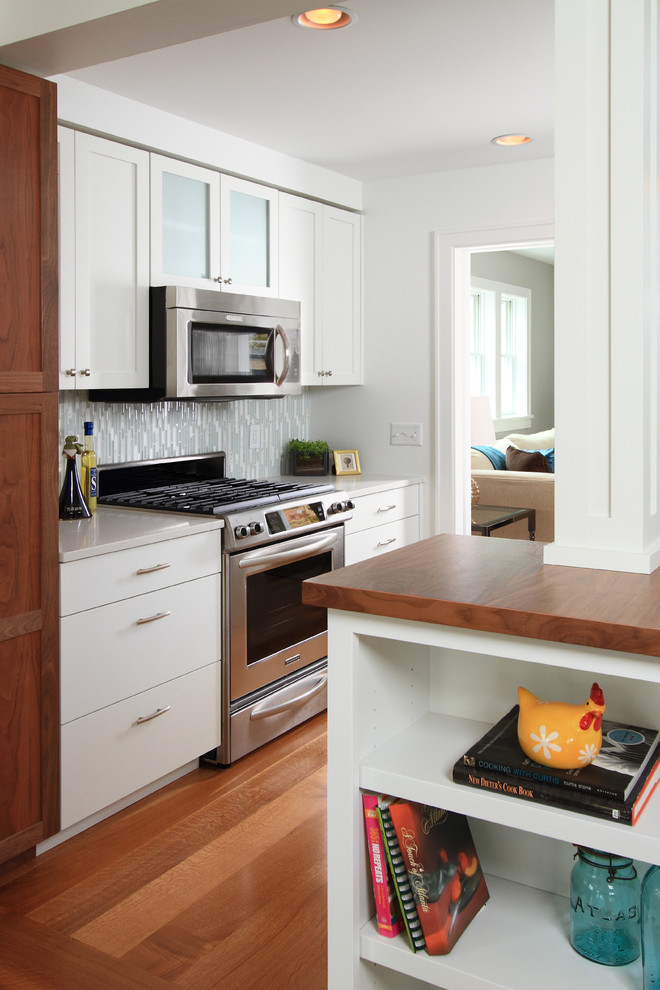 Foto på ett funkis kök, med träbänkskiva, skåp i shakerstil, vita skåp, grått stänkskydd, stänkskydd i stickkakel och rostfria vitvaror