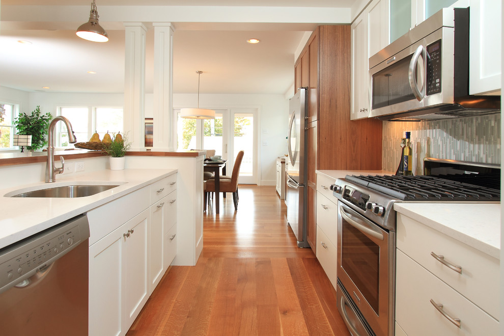 Cette image montre une cuisine ouverte parallèle design avec un évier encastré, une crédence grise, une crédence en carreau briquette et un électroménager en acier inoxydable.