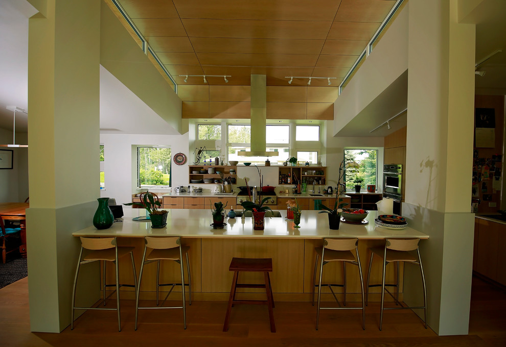 Пример оригинального дизайна: огромная параллельная кухня-гостиная в современном стиле с врезной мойкой, плоскими фасадами, светлыми деревянными фасадами, техникой из нержавеющей стали и паркетным полом среднего тона без острова