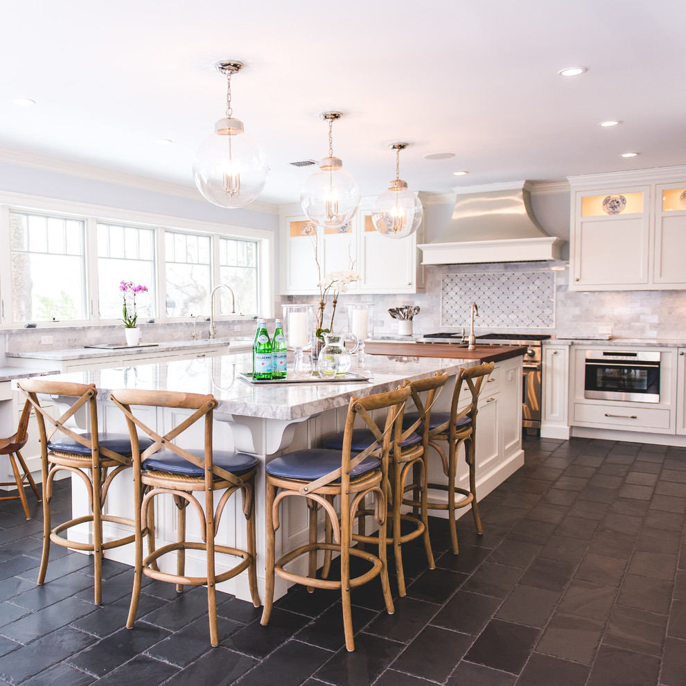 This is an example of a large rural kitchen/diner in New York with an island, a submerged sink, recessed-panel cabinets, white cabinets, engineered stone countertops, grey splashback, marble splashback, stainless steel appliances, slate flooring and black floors.