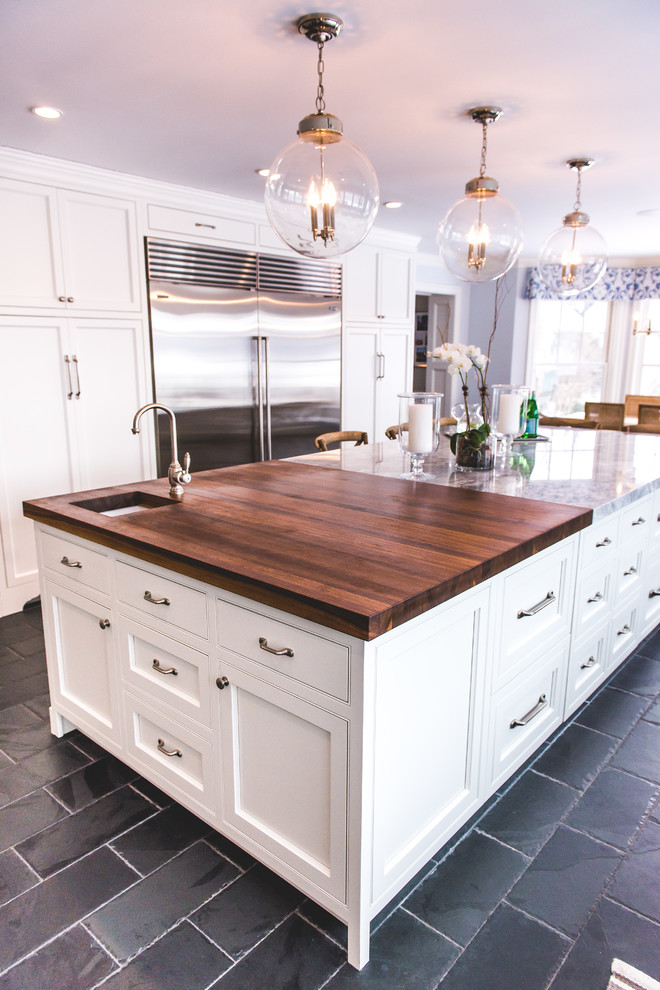 Photo of a large farmhouse u-shaped kitchen/diner in New York with a submerged sink, recessed-panel cabinets, white cabinets, engineered stone countertops, stainless steel appliances, slate flooring, an island, black floors, grey splashback and marble splashback.