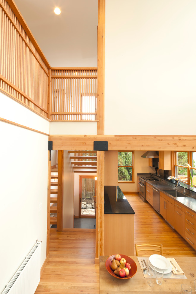 Стильный дизайн: кухня в современном стиле с обеденным столом, плоскими фасадами и фасадами цвета дерева среднего тона - последний тренд