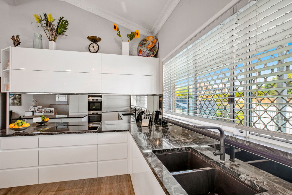 Moderne Wohnküche mit weißen Schränken, Granit-Arbeitsplatte und Glasrückwand in Sunshine Coast