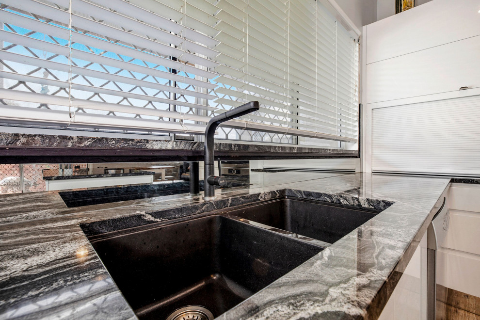 Minimalist eat-in kitchen photo in Sunshine Coast with white cabinets, granite countertops and glass sheet backsplash