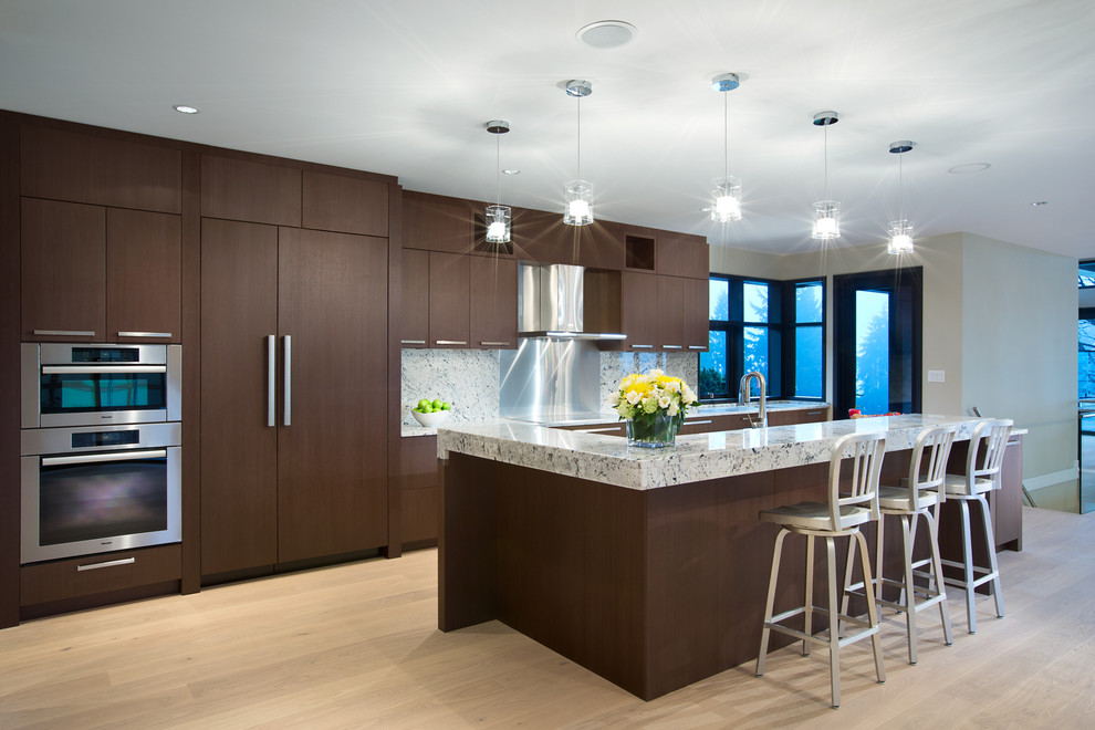 Foto de cocina contemporánea con electrodomésticos de acero inoxidable, una isla, armarios con paneles lisos, puertas de armario de madera en tonos medios y suelo de madera clara