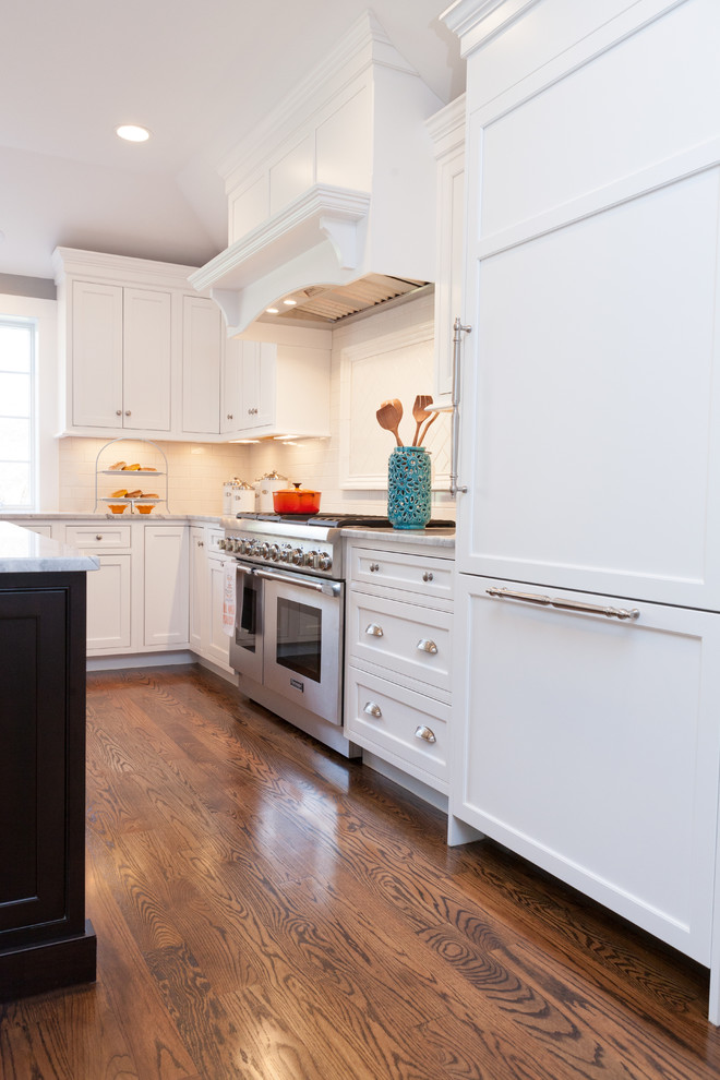 Immagine di una grande cucina classica con ante in stile shaker, ante bianche, elettrodomestici in acciaio inossidabile, pavimento in legno massello medio, lavello sottopiano e paraspruzzi bianco
