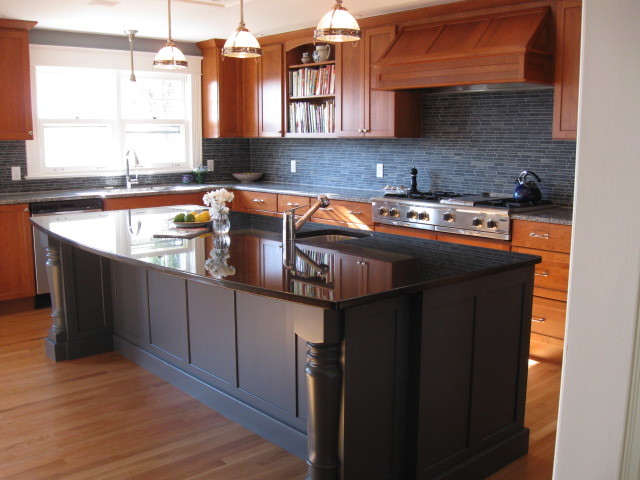 Modelo de cocina tradicional renovada con fregadero encastrado, puertas de armario de madera oscura, salpicadero azul, electrodomésticos de acero inoxidable, suelo de madera en tonos medios y una isla
