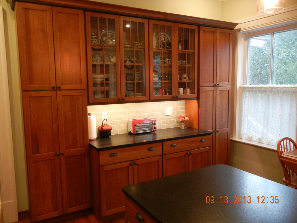 This is an example of a traditional kitchen in Burlington with medium wood cabinets, beige splashback, medium hardwood flooring and an island.