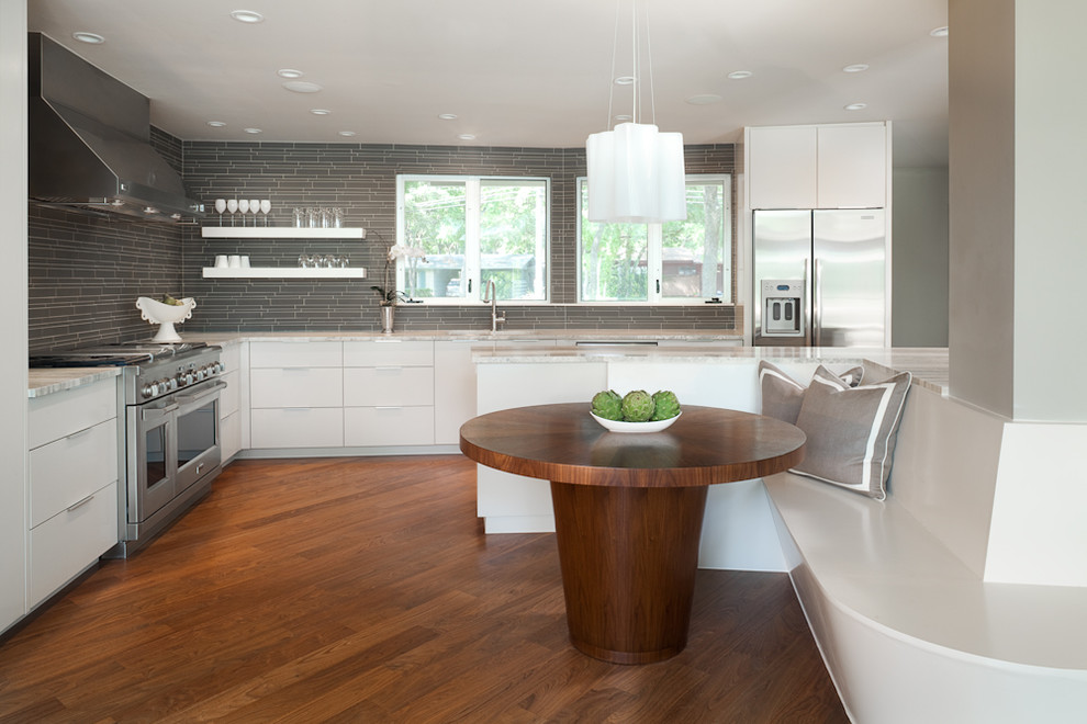 Moderne Küche in L-Form mit Küchengeräten aus Edelstahl, flächenbündigen Schrankfronten, weißen Schränken und Küchenrückwand in Grau in Austin