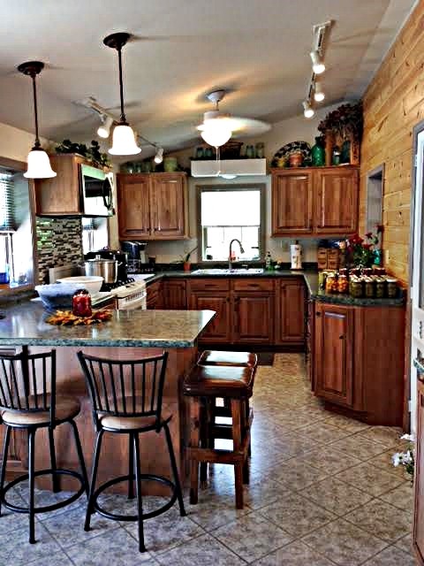 Rustik inredning av ett mellanstort kök, med en nedsänkt diskho, luckor med upphöjd panel, skåp i mörkt trä, granitbänkskiva, flerfärgad stänkskydd, stänkskydd i stickkakel, vita vitvaror, vinylgolv och en halv köksö