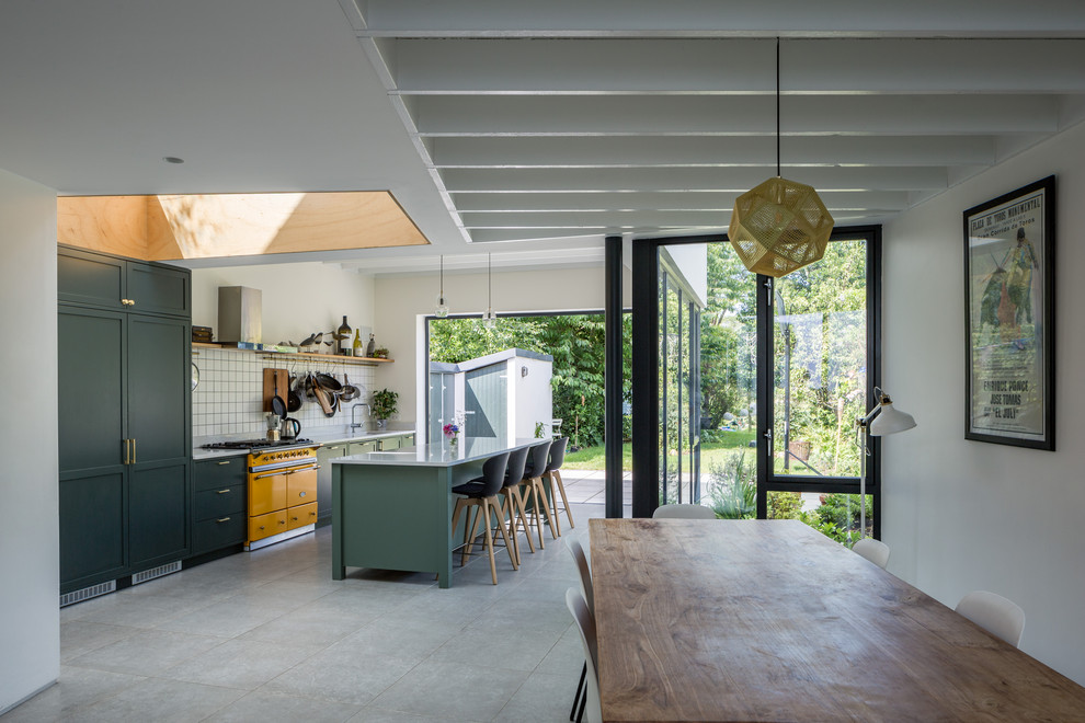 На фото: параллельная кухня в современном стиле с обеденным столом, фасадами в стиле шейкер, зелеными фасадами, белым фартуком, цветной техникой, островом и серым полом