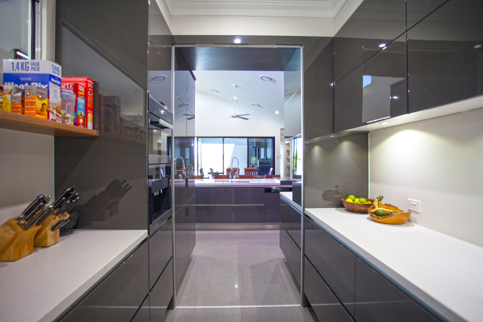 Inspiration for a large contemporary galley kitchen pantry in Other with stainless steel appliances, an island, flat-panel cabinets, grey cabinets, granite worktops, ceramic flooring, grey floors and white worktops.