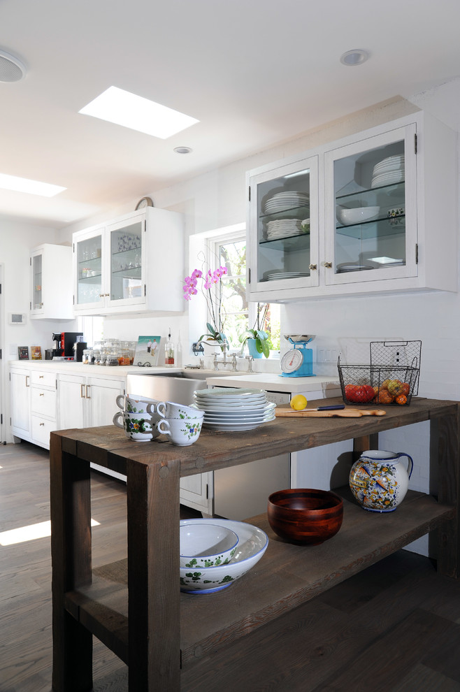 Klassische Küche mit Landhausspüle, Glasfronten, weißen Schränken, Küchenrückwand in Weiß und dunklem Holzboden in Los Angeles