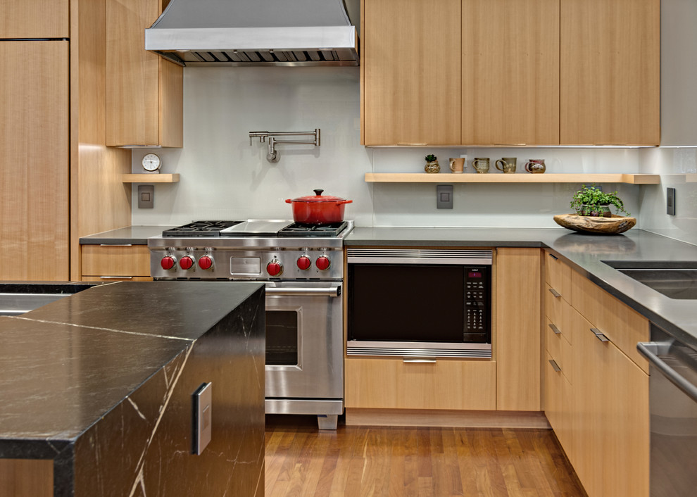 Idéer för mellanstora funkis grönt kök, med en undermonterad diskho, släta luckor, skåp i mellenmörkt trä, bänkskiva i täljsten, grönt stänkskydd, glaspanel som stänkskydd, rostfria vitvaror, mellanmörkt trägolv, en köksö och orange golv