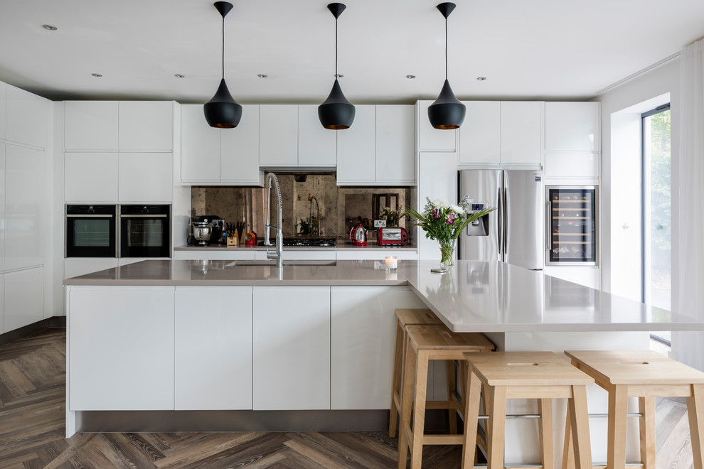 Einzeilige, Mittelgroße Moderne Küche mit flächenbündigen Schrankfronten, weißen Schränken, Rückwand aus Spiegelfliesen, Küchengeräten aus Edelstahl, dunklem Holzboden, Kücheninsel und braunem Boden in London