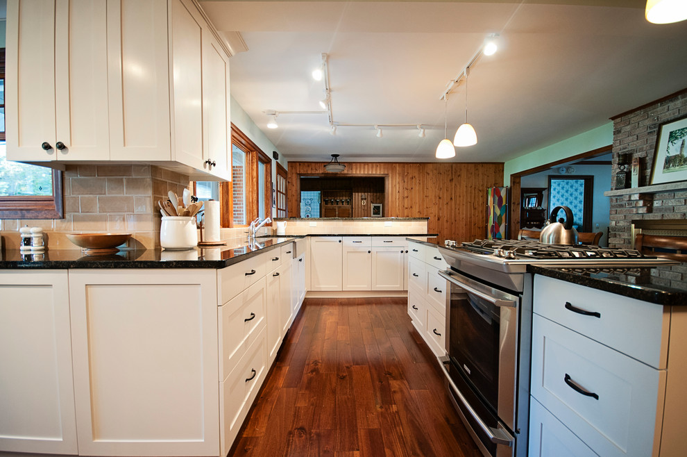 Klassisk inredning av ett avskilt, stort kök, med en rustik diskho, luckor med infälld panel, vita skåp, granitbänkskiva, beige stänkskydd, stänkskydd i keramik, rostfria vitvaror, mellanmörkt trägolv och en köksö