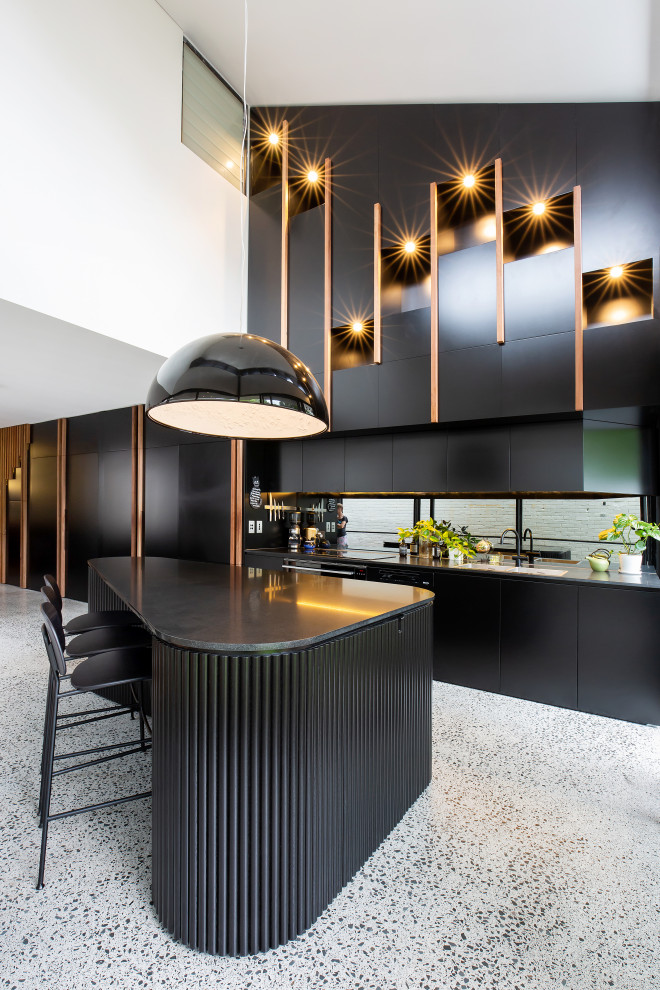 Modern inredning av ett mellanstort svart linjärt svart kök, med en nedsänkt diskho, skåp i shakerstil, svarta skåp, bänkskiva i kvarts, svart stänkskydd, spegel som stänkskydd, svarta vitvaror, terrazzogolv, en köksö och grått golv