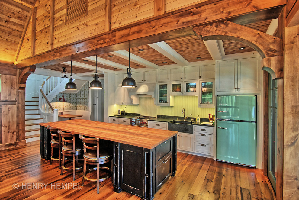 Large rustic galley open plan kitchen in Minneapolis with a belfast sink, shaker cabinets, distressed cabinets, granite worktops, green splashback, coloured appliances, medium hardwood flooring and an island.