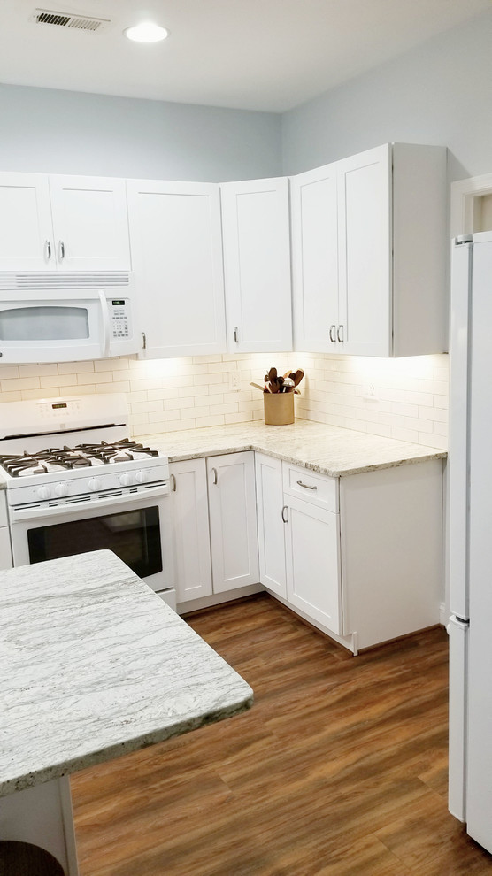Inspiration for a small transitional l-shaped linoleum floor and brown floor enclosed kitchen remodel in Baltimore with a single-bowl sink, shaker cabinets, white cabinets, granite countertops, white backsplash, ceramic backsplash, white appliances, an island and gray countertops