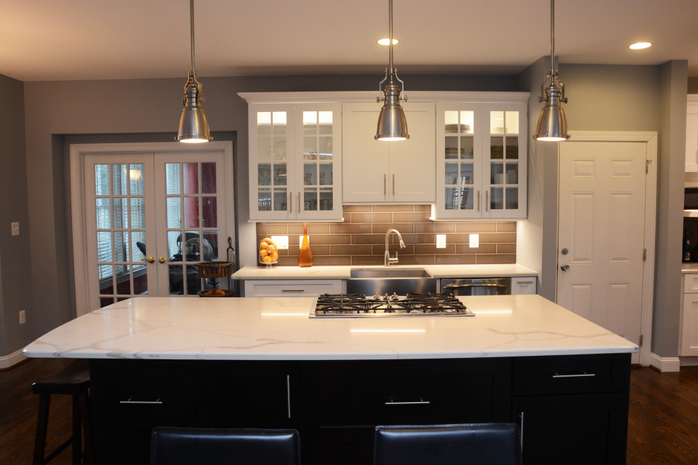 Inspiration for a large modern l-shaped open plan kitchen in Baltimore with a belfast sink, shaker cabinets, white cabinets, engineered stone countertops, grey splashback, stainless steel appliances, dark hardwood flooring, an island, brown floors and white worktops.