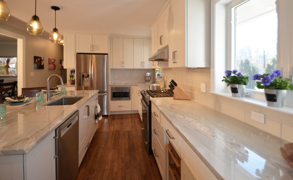 Inspiration for a large transitional u-shaped medium tone wood floor open concept kitchen remodel in DC Metro with an undermount sink, shaker cabinets, white cabinets, quartzite countertops, white backsplash, glass tile backsplash, stainless steel appliances and an island