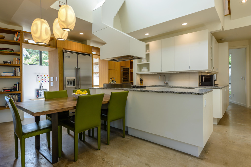 Eat-in kitchen - large contemporary l-shaped concrete floor and gray floor eat-in kitchen idea in Austin with flat-panel cabinets, white cabinets, white backsplash, stainless steel appliances, a farmhouse sink and an island