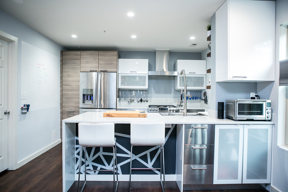 Immagine di una cucina minimal con ante grigie, paraspruzzi blu, elettrodomestici in acciaio inossidabile, parquet scuro e penisola
