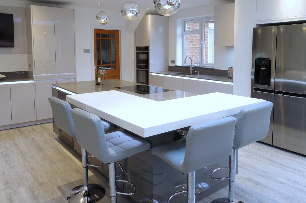 Large modern kitchen/diner in Kent with grey cabinets, an island, grey floors and white worktops.