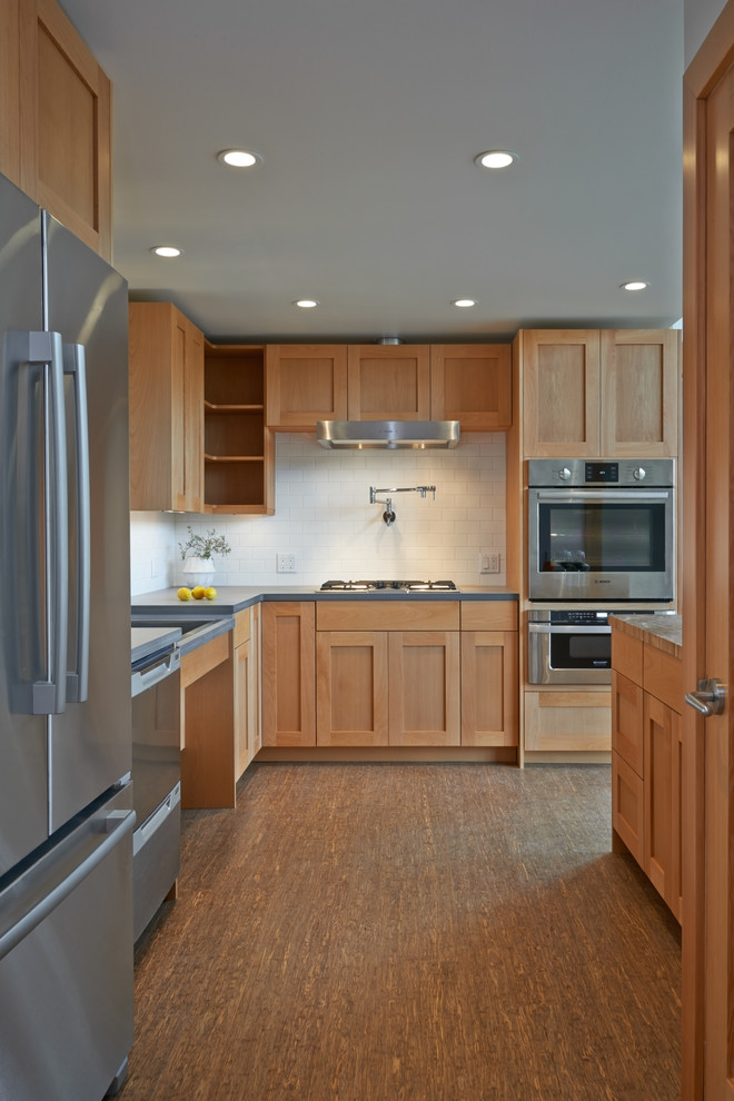 Example of a mid-sized transitional l-shaped bamboo floor and brown floor eat-in kitchen design in Seattle with shaker cabinets, light wood cabinets, white backsplash, subway tile backsplash, stainless steel appliances, a double-bowl sink, solid surface countertops and an island