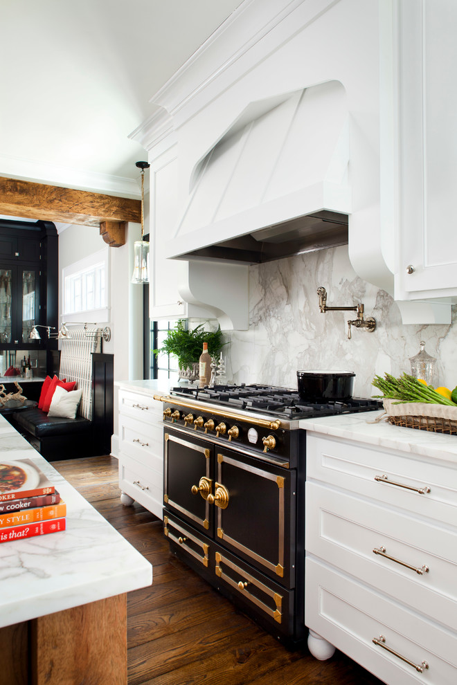 Example of a mid-sized classic l-shaped medium tone wood floor enclosed kitchen design in Atlanta with recessed-panel cabinets, white cabinets, white backsplash, stone slab backsplash, black appliances, marble countertops, an undermount sink and an island
