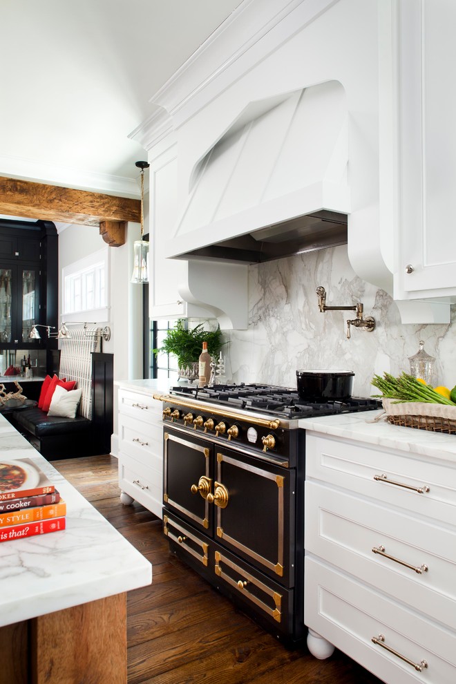 Foto på ett avskilt, mellanstort vintage l-kök, med svarta vitvaror, en undermonterad diskho, luckor med infälld panel, vita skåp, marmorbänkskiva, vitt stänkskydd, stänkskydd i sten, mellanmörkt trägolv och en köksö